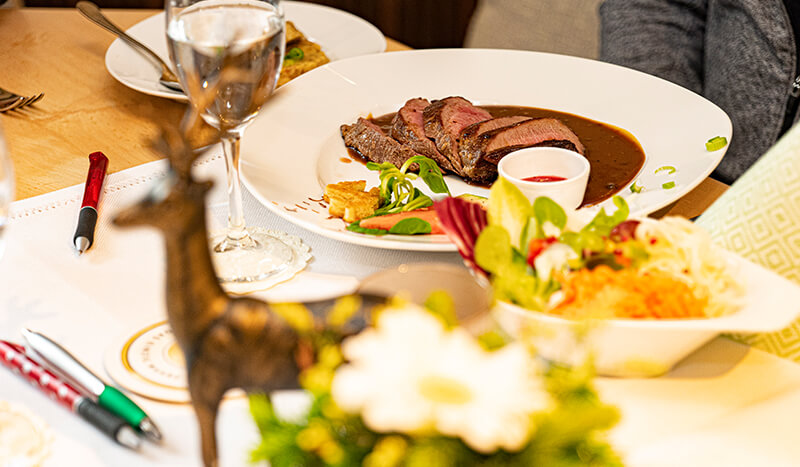 Freizeit & Tourismus - Gastronomien in Wadersloh - Bild von einem Tisch in einem Restaurant mit einem Fleisch auf einem Teller und Rehdekoration